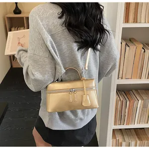 Detail of a metallic light gold handbag featuring a dual zipper and leather tag decoration