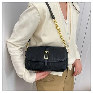 Detail of black vertical striped crossbody bag with gold chain strap on a female model