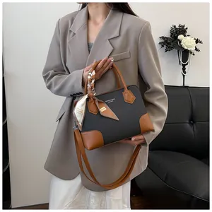 Détail du sac à main gris tissé avec finitions en cuir marron et foulard en soie
