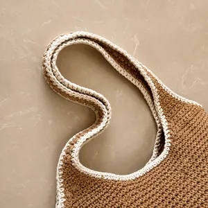 Close-up of the comfortable woven handle of this brown and beige knit tote bag