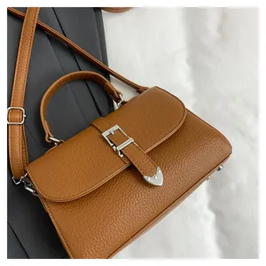 Détail du sac en cuir litchi caramel avec boucle en métal argenté et bandoulière réglable