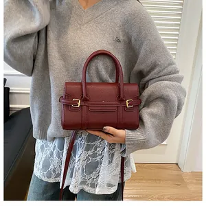 Vue détaillée du sac à main bordeaux en cuir litchi avec boucles en métal doré