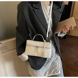 Detail of white leather rectangular handbag featuring dual zipper closure and top handle