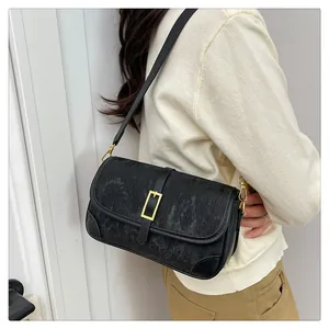 Detail of black crossbody bag with gold metal buckle and vertical stripe texture