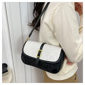 Detail view of black and white color-block handbag with gold buckle on a model