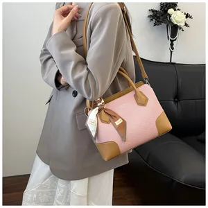 Détail du sac à main tissé rose avec bandoulière en cuir et foulard décoratif sur l'anse