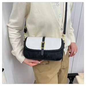 Detail of contrast stitch shoulder bag featuring white corduroy texture and black leather