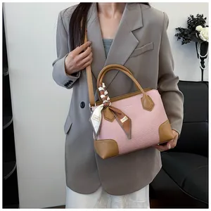 Détail du sac à main tissé rose avec finitions en cuir marron et foulard décoratif