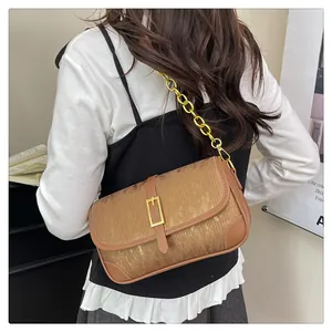 Detail view of caramel brown crossbody bag featuring vertical texture and gold chain strap