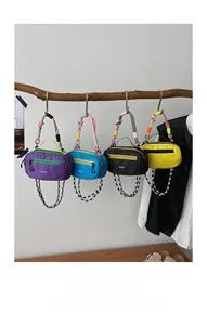 Dettaglio che mostra quattro mini borse in nylon colorate appese con cinghie intrecciate