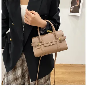 Détail macro du sac à main en cuir marron clair avec motif litchi et boucle dorée élégante