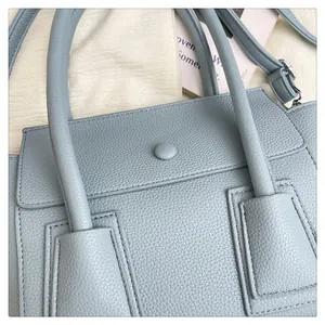 Détail du sac à main bleu clair en cuir grainé avec poignées et fermeture à rabat