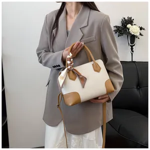 Détail d'un sac à main tissé beige élégant avec bordure en cuir marron et foulard de mode