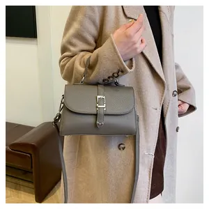 Détail du sac à main gris foncé en cuir grainé avec boucle argentée sur un manteau