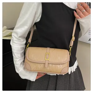 Detailed view of beige crossbody bag featuring vertical texture and golden buckle closure
