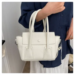 Détail d'un sac à main blanc en cuir grainé avec rabat et finitions métalliques argentées