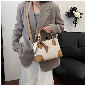 Détail du sac à main tissé avec garniture en cuir caramel et foulard en soie décoratif