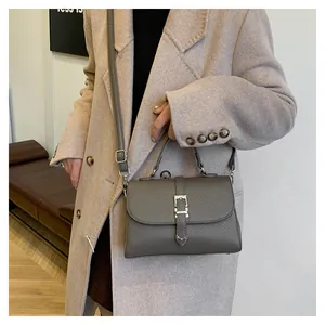 Détail du sac à main en cuir taupe à texture litchi avec boucle argentée et bandoulière