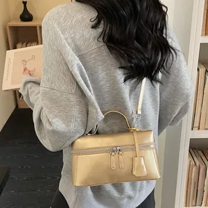 Golden metallic rectangular crossbody bag with dual zipper and detachable shoulder strap