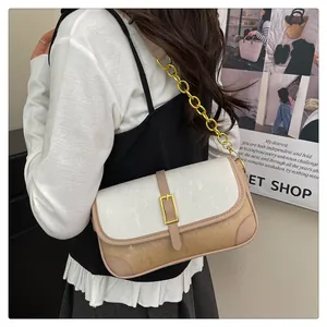 Detail of a minimalist crossbody bag with two-tone fabric, gold buckle, and chain strap