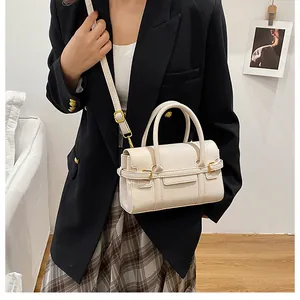 Modèle portant un sac à main beige texture litchi avec détails en métal doré