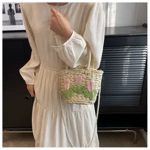 Detail of straw bag with knit tulip pattern, drawstring liner and pearl strap