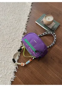Dettaglio macro di una borsa a tracolla viola a scacchi con cerniere verde neon a contrasto