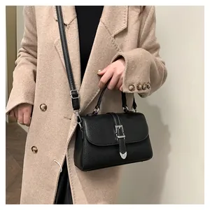 Détail du sac à main noir en cuir grainé avec une boucle argentée en forme de coeur