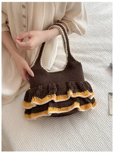 Close-up of knit tote bag with ruffles and contrasting orange trim on dark brown fabric