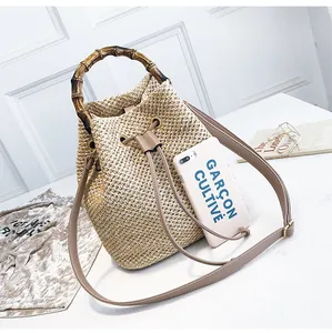 Detail of straw bucket bag with vintage bamboo handle and drawstring closure