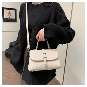 Détail d'un sac à main beige grainé avec boucles argentées et bandoulière réglable
