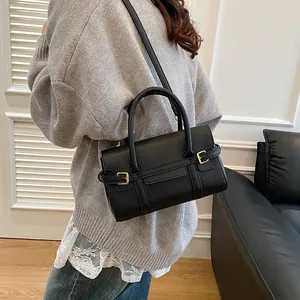 Sac à main noir classique à motif litchi avec boucles dorées porté par un mannequin
