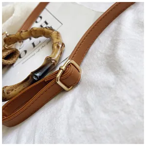 Detail of vintage bamboo handle and brown leather strap with gold metal hardware