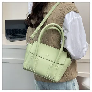 Détail du sac à main vert avocat avec texture litchi et bandoulière amovible