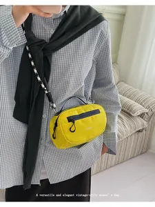 Dettaglio della borsa in nylon giallo con tracolla decorata e tasca frontale con cerniera