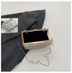 Close-up of champagne gold evening clutch with glitter texture and gold chain strap