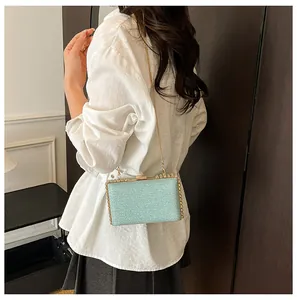 Detail of mint green sequin box bag with gold chain strap shown on a model