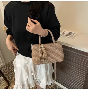 Beige pleated tote bag featuring decorative double tassels and adjustable shoulder strap