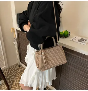 Detail of khaki tote bag featuring fish scale pleated texture and long tassel pendants