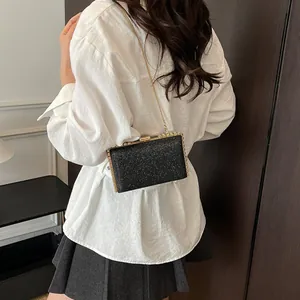 Sparkling black sequin box clutch with gold chain strap worn by a model in casual attire