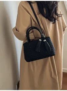 Detailed shot of black tote bag with fish scale pleated texture and tassel charms
