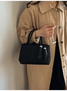 Detail of black tote bag showing fish-scale pleats and rhinestones on tassels