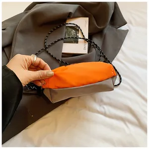 Detail der Nylon-Umhängetasche in Orange und Taupe mit geflochtenem Schultergurt