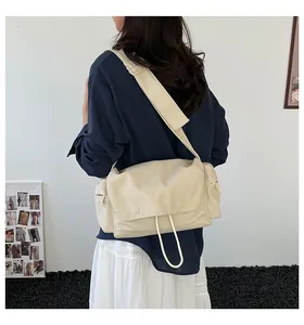 Dettaglio di una borsa a tracolla in tela crema con tracolla larga e tasche laterali