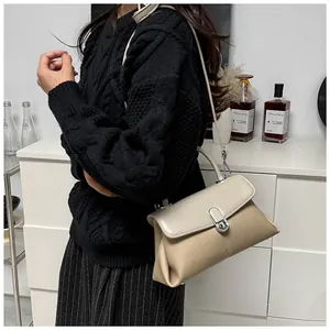 Vue détaillée du sac bandoulière beige et kaki avec fermoir argenté porté par un mannequin