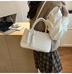 Detail of white pleated tote bag with fishtail texture and rhinestone tassel accents