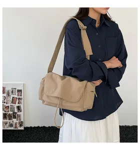 Dettaglio della tracolla larga regolabile e delle tasche laterali della borsa beige in tela