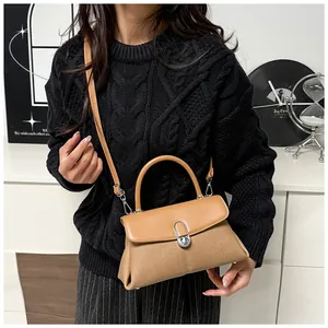 Détails du sac à main en cuir et tissu marron porté par un mannequin avec bandoulière