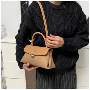 Détail d'un sac à main en cuir marron avec boucle en métal en fer à cheval et poignée courte