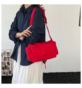 Vista laterale della borsa messenger in nylon rosso con tracolla larga sul modello